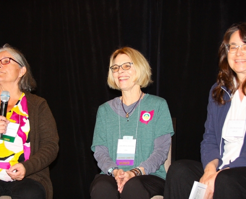 Three women sitting on a panel sharing in a dicussion.